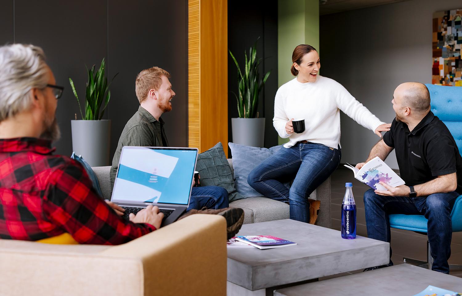 4 Personen unterhalten sich in einem Aufenthaltsbereich von codecentric, Person im Vordergrund hat ein Notebook auf dem Schoß