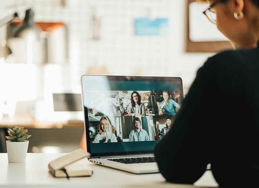 Person sitzt vor Notebook, auf dem Monitor Teilnehmer einer Videokonferenz