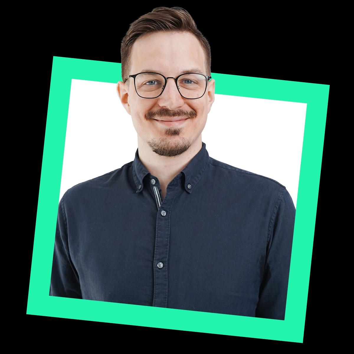 Profilbild von Dominik Fladung im Hemd und mit Brille