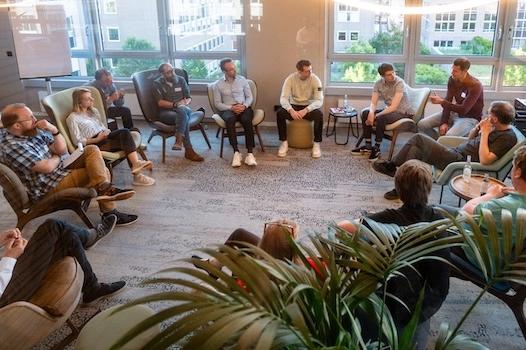 Gäste und Mitarbeitende der codecentric AG sitzen bei einem Event im Stuhlkreis und tauschen sich aus