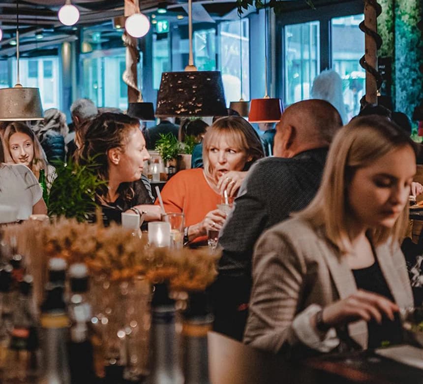 Innenaufnahme eines Restaurants, viele verschiedene Personen am Essen, Trinken und reden.