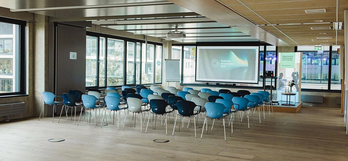 Konferenzraum im codecentric Standort Plaza München mit Stuhlreihen vor einer Bühne